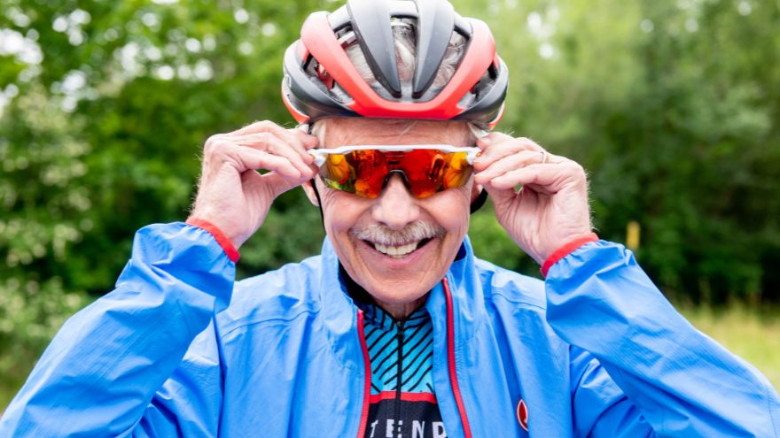 older male cyclist donning sunglasses while smiling
